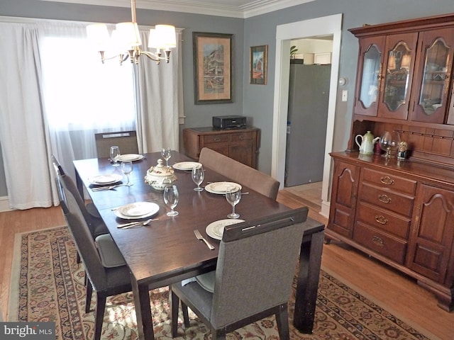 dining area with crown molding, light wood-type flooring, and a chandelier