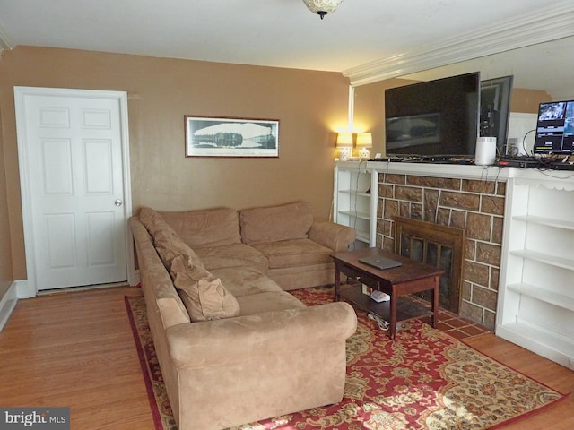 living room with a fireplace, ornamental molding, and light hardwood / wood-style floors