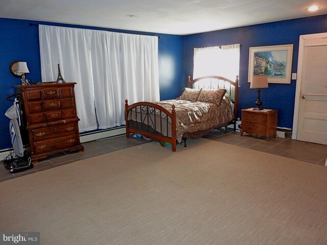 bedroom featuring a baseboard heating unit and dark tile flooring