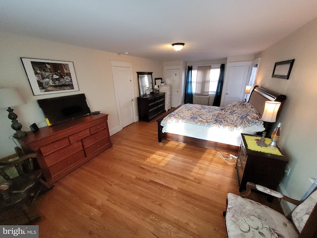 bedroom with radiator heating unit and light wood-type flooring