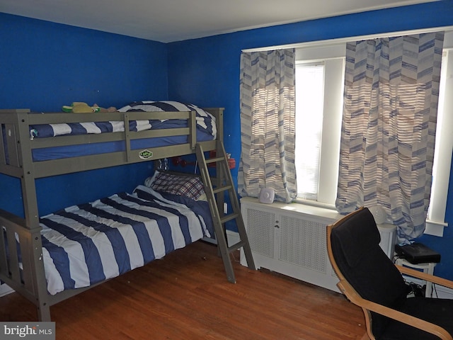 bedroom with dark hardwood / wood-style flooring and radiator