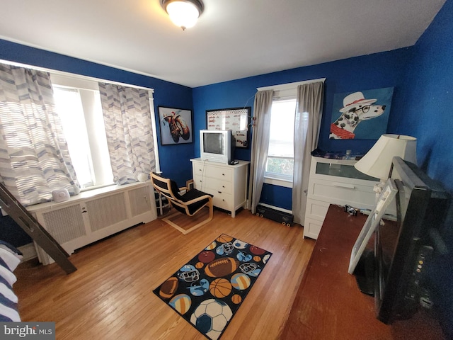 bedroom featuring radiator and light hardwood / wood-style flooring