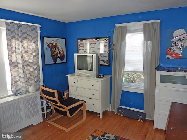 sitting room with dark wood-type flooring and radiator heating unit