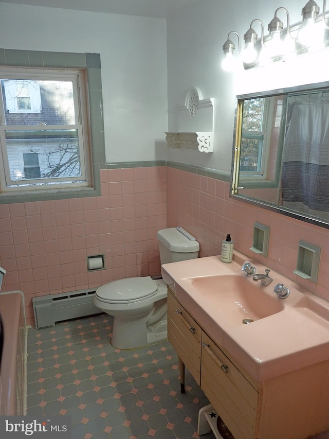 bathroom featuring tile flooring, toilet, vanity, a baseboard heating unit, and tile walls