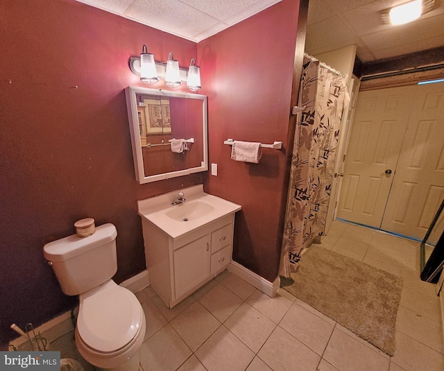 bathroom featuring oversized vanity, tile flooring, toilet, and a drop ceiling