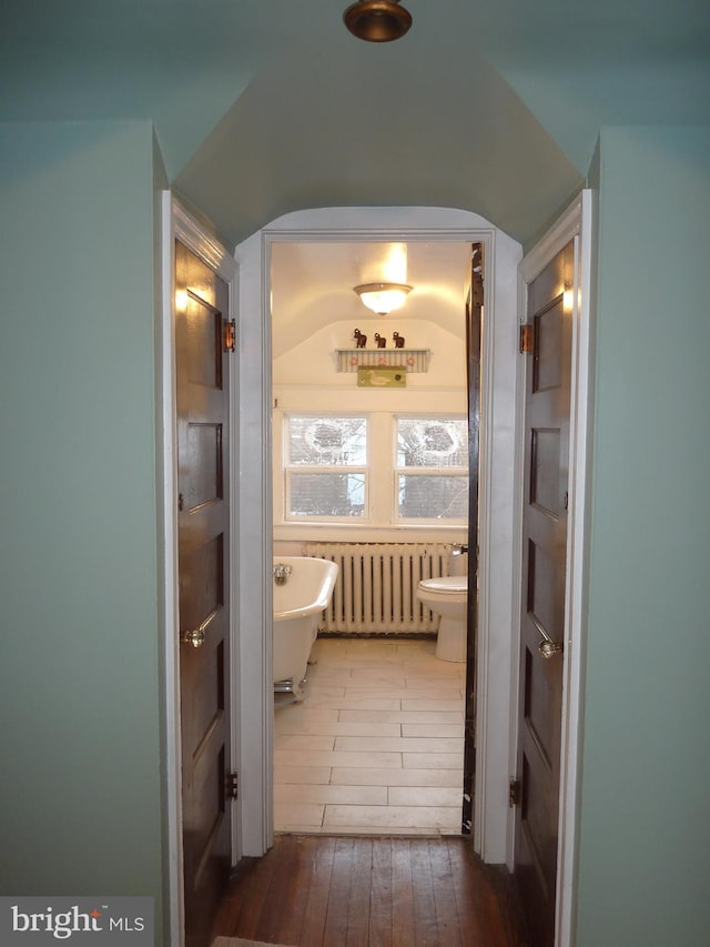 bathroom with a bath to relax in, tile floors, radiator, and toilet