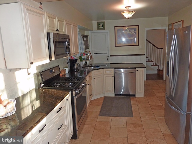 kitchen with sink, appliances with stainless steel finishes, dark stone countertops, backsplash, and light tile flooring