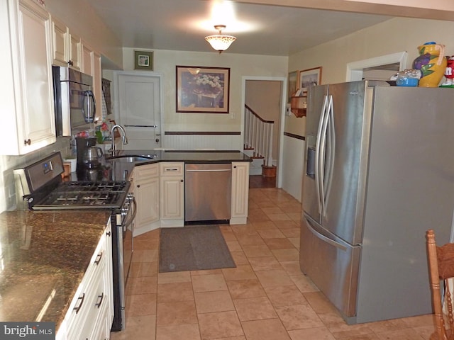 kitchen with sink, light tile floors, dark stone counters, white cabinets, and stainless steel appliances