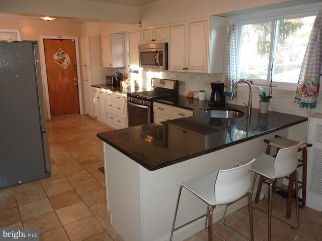 kitchen featuring kitchen peninsula, sink, light tile floors, stainless steel appliances, and white cabinetry