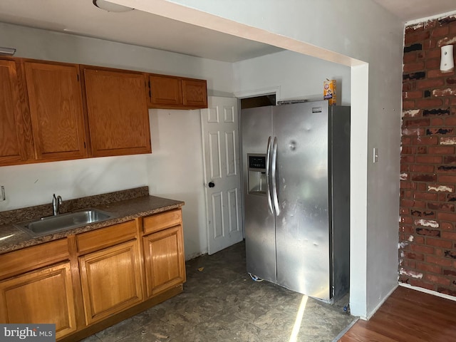 kitchen featuring dark stone countertops, stainless steel fridge with ice dispenser, dark wood-type flooring, and sink