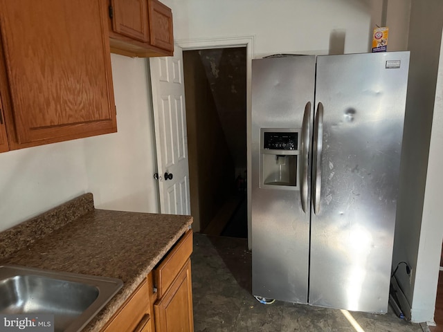 kitchen with stainless steel fridge, dark tile floors, and sink