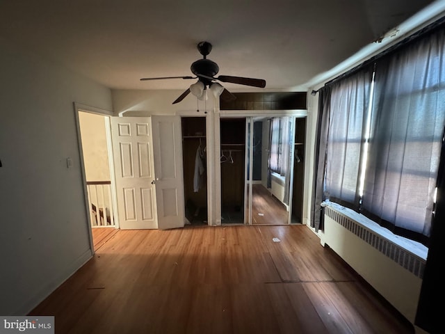 unfurnished bedroom with light wood-type flooring, ceiling fan, and radiator