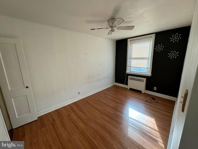 spare room featuring dark hardwood / wood-style flooring, ceiling fan, and radiator