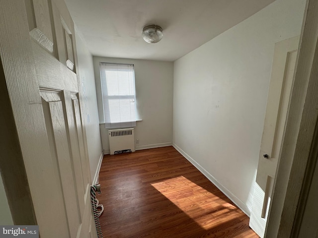 empty room with radiator heating unit and dark wood-type flooring