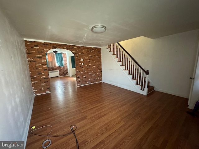 interior space with brick wall, dark hardwood / wood-style flooring, and radiator