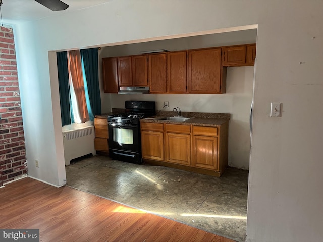 kitchen with hardwood / wood-style flooring, ceiling fan, black gas range oven, radiator, and sink