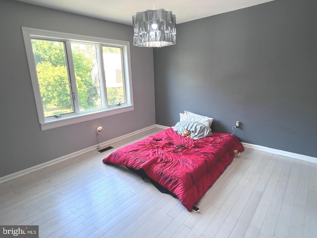 bedroom with a chandelier and light hardwood / wood-style flooring