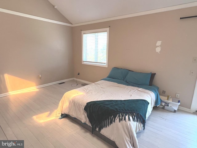 bedroom featuring wood-type flooring, ornamental molding, and vaulted ceiling