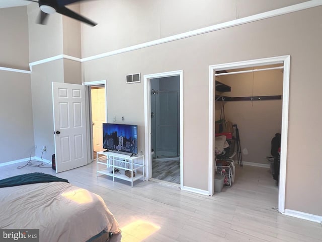 bedroom with ceiling fan, light hardwood / wood-style floors, a high ceiling, and a closet