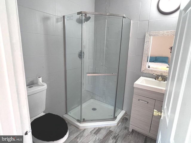 bathroom with vanity, toilet, walk in shower, and tile walls