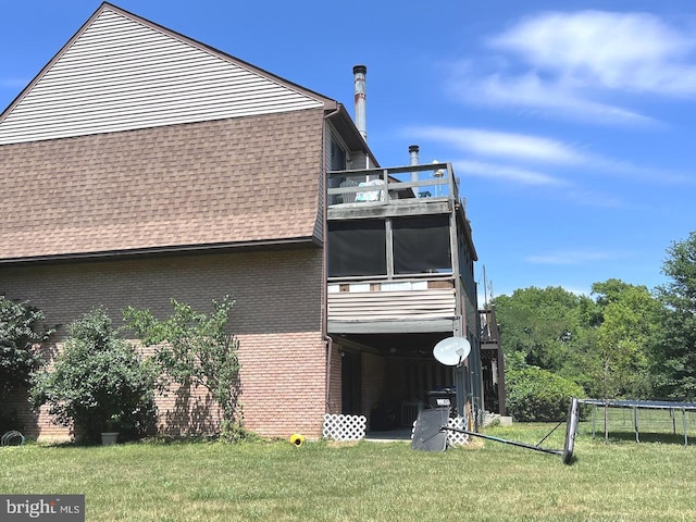 view of side of property with a lawn, a balcony, and a trampoline