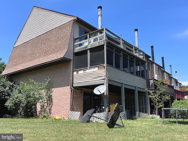 back of house featuring a balcony and a lawn