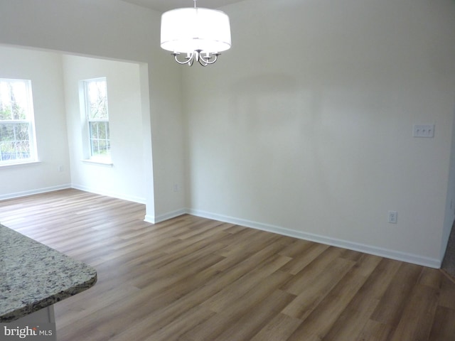 empty room featuring an inviting chandelier and hardwood / wood-style floors