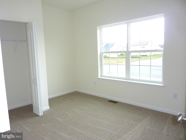 unfurnished bedroom featuring a closet, multiple windows, and light colored carpet