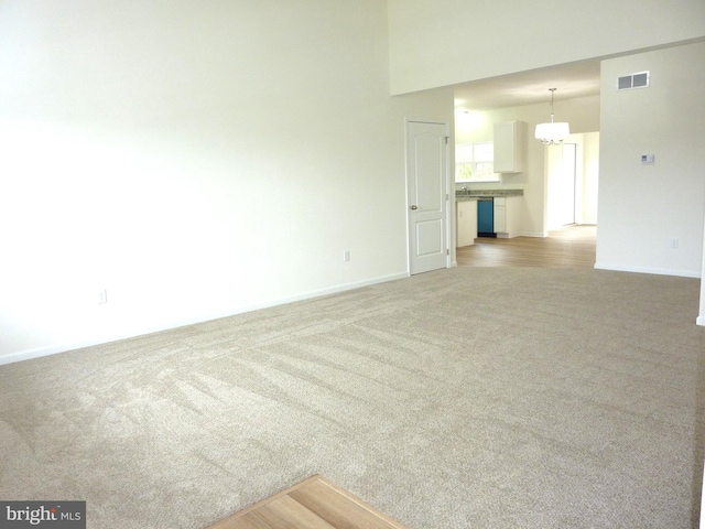 unfurnished room with a chandelier, carpet flooring, and a high ceiling