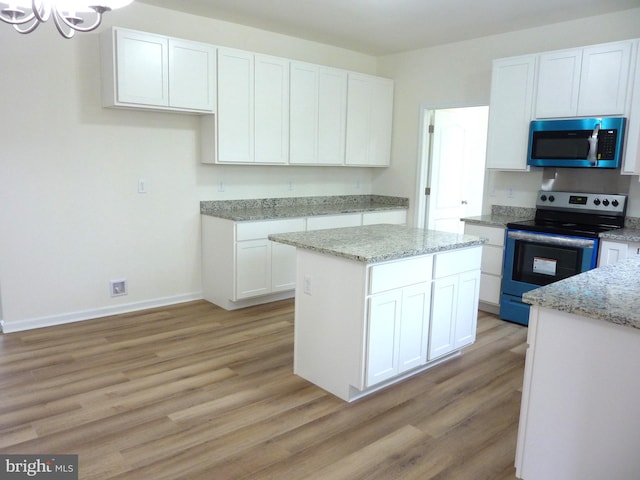 kitchen with a kitchen island, stainless steel appliances, white cabinets, and light hardwood / wood-style flooring