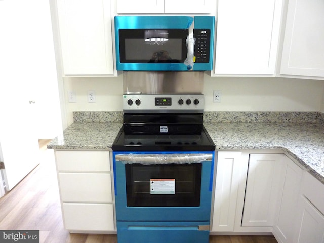 kitchen featuring white cabinets, light wood-type flooring, appliances with stainless steel finishes, and light stone counters