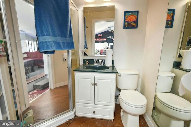 bathroom with wood-type flooring, a shower with door, oversized vanity, and toilet