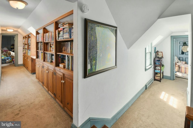 hall with vaulted ceiling, light carpet, and a baseboard heating unit