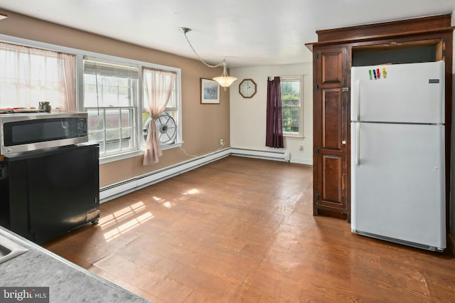 kitchen with hardwood / wood-style floors, hanging light fixtures, a baseboard heating unit, and white fridge