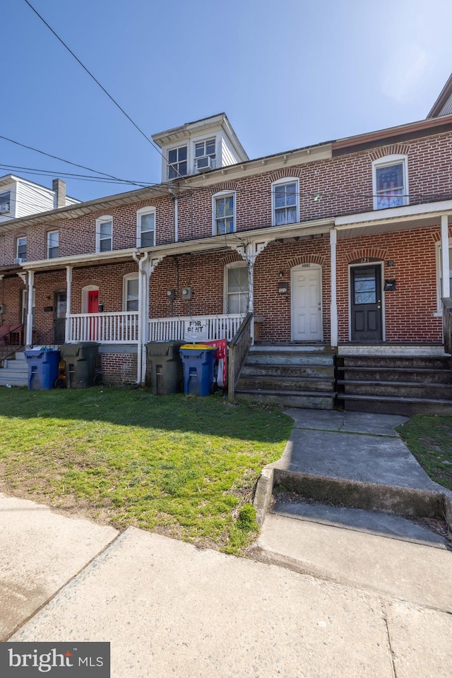 townhome / multi-family property featuring a front yard and covered porch