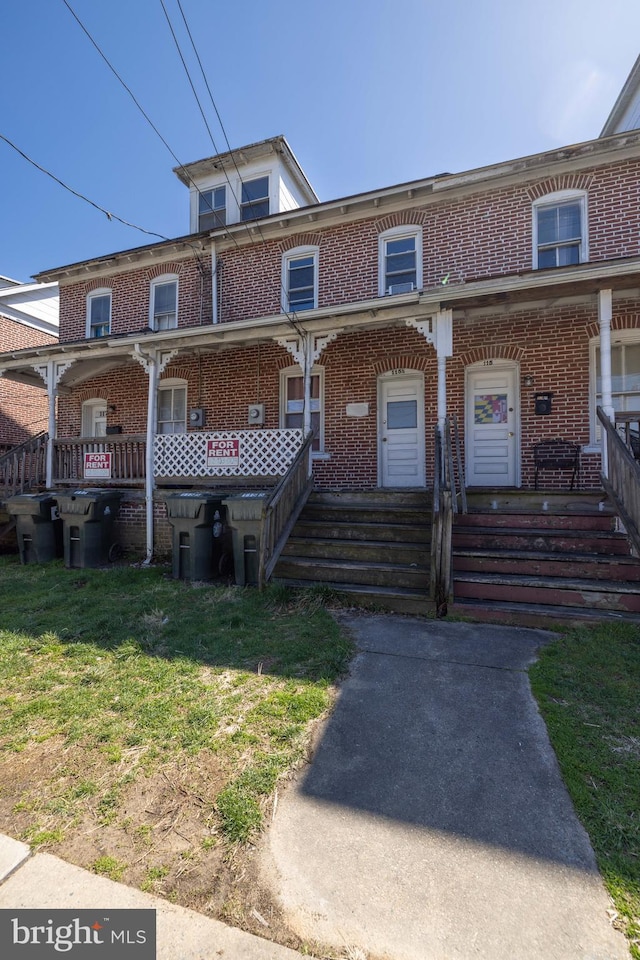 view of property with covered porch and a front lawn