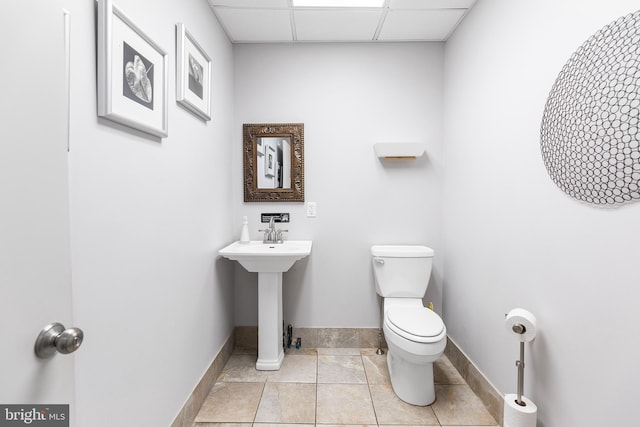 bathroom featuring toilet, tile floors, and a paneled ceiling