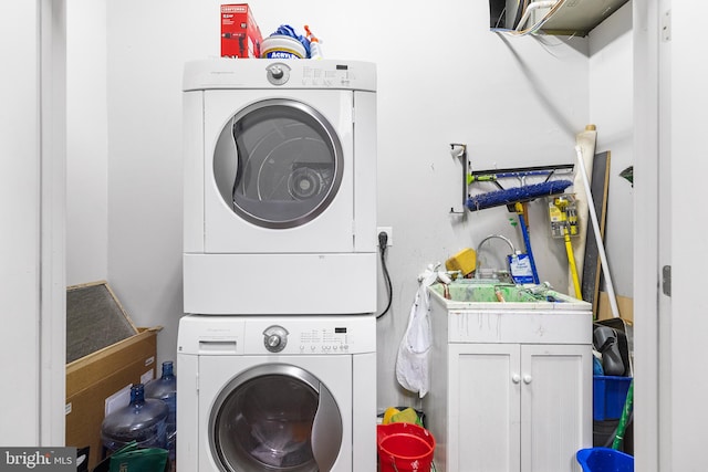 laundry area featuring cabinets and stacked washer / drying machine