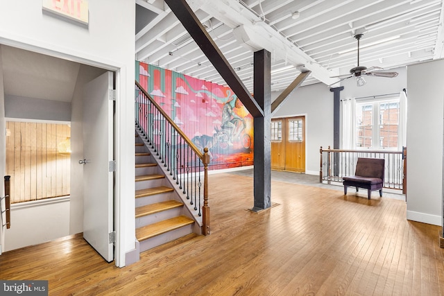 staircase with ceiling fan, light hardwood / wood-style flooring, and a high ceiling