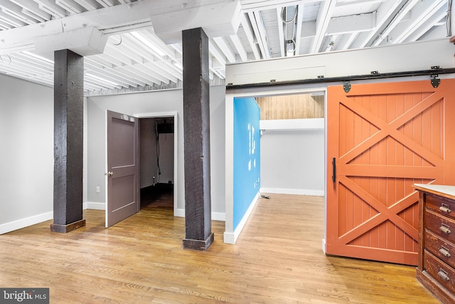 basement featuring light hardwood / wood-style flooring and a barn door