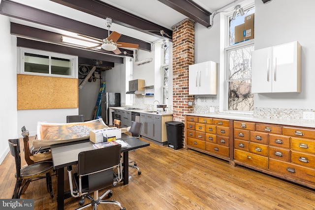 office area featuring ceiling fan, brick wall, light hardwood / wood-style floors, sink, and beam ceiling