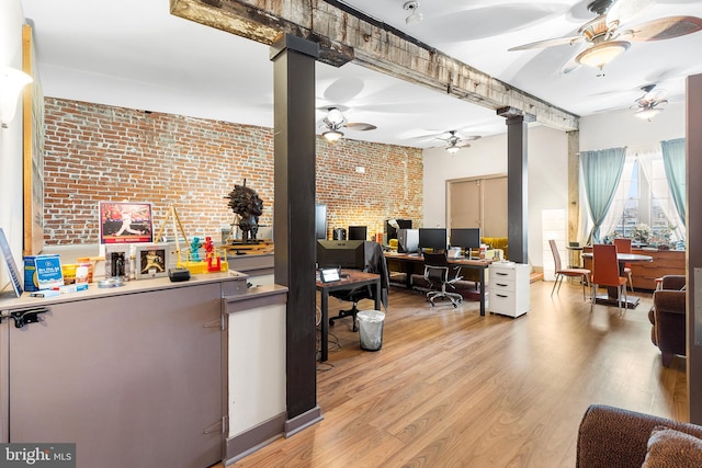 interior space featuring brick wall, ceiling fan, light wood-type flooring, and ornate columns