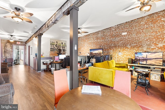 office space featuring light hardwood / wood-style flooring, ceiling fan, decorative columns, and brick wall