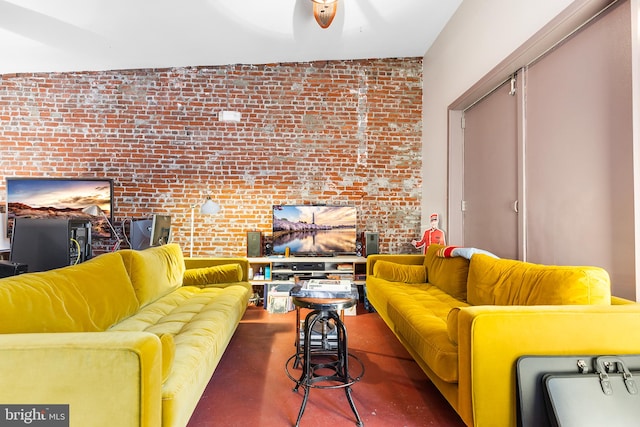 living room featuring ceiling fan and brick wall