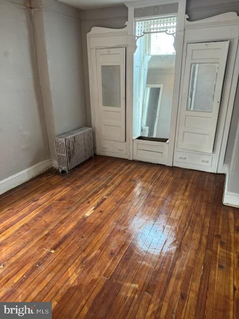 spare room with dark hardwood / wood-style floors and radiator heating unit