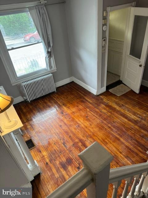 unfurnished living room featuring radiator and dark hardwood / wood-style flooring