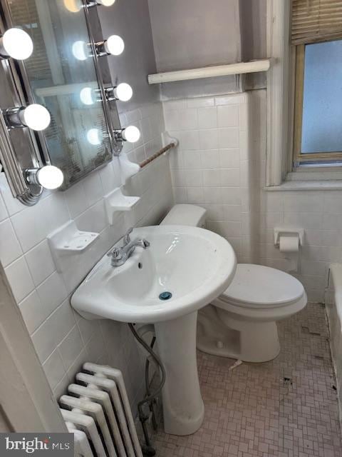 bathroom with radiator, toilet, and tile walls