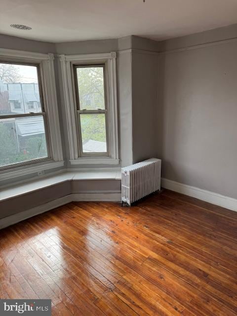 spare room featuring wood-type flooring and radiator