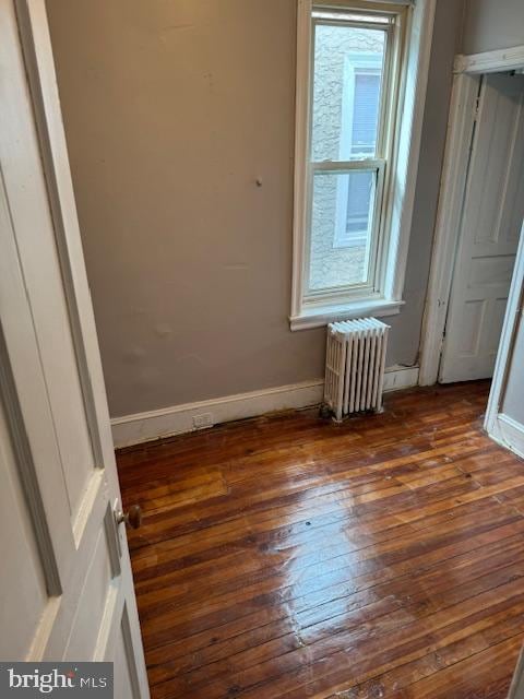 empty room featuring radiator heating unit and dark hardwood / wood-style flooring