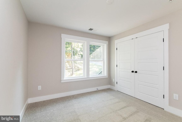 unfurnished bedroom with a closet and light carpet